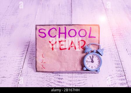 Word writing text School Year. Business photo showcasing the annual period of sessions of an educational institution Mini blue alarm clock stand tilte