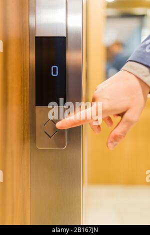 Close up of businessman hand pressing modern elevator button. Space for copy. Stock Photo