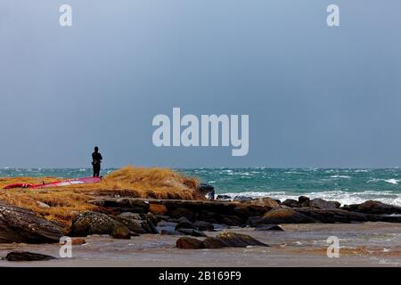 Wind surfer taking a break while watching the storm before getting back in the water Stock Photo