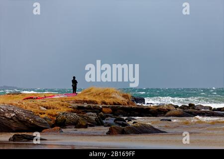 Wind surfer taking a break while watching the storm before getting back in the water Stock Photo