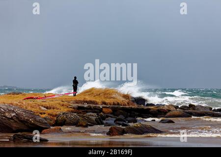 Wind surfer taking a break while watching the storm before getting back in the water Stock Photo