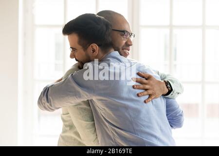 African and Caucasian guys hugging glad to see each other Stock Photo