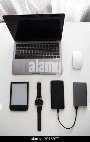 flatlay of different objects as laptop computer mouse phone smart watch e-book powerbank cellphone Stock Photo