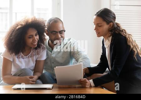Mixed-race couple discussing contract terms during meeting with realtor