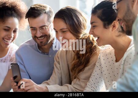 Biracial woman holding smartphone having fun online with multiethnic friends Stock Photo