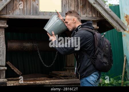 Man drinks from well with water Stock Photo