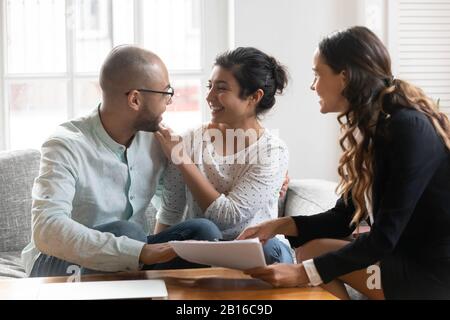 Multi-ethnic couple feels satisfied with negotiations results with agent Stock Photo