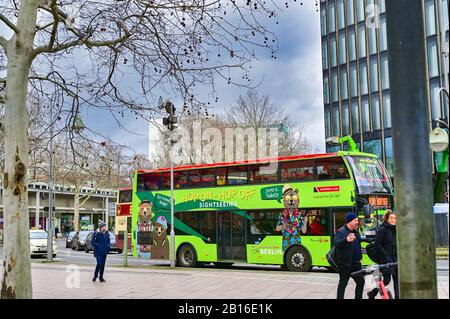 Berlin, Germany - February 21, 2020: Street scene with a green hop-on-hop-of bus for tourists in downtown Berlin, Germany. Stock Photo