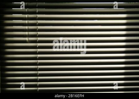 Venetian blind with the sun peeping through its slats Stock Photo