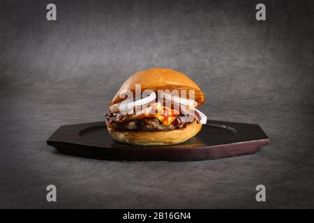 Beef burger - Classic cheese burger  with beef patty, pickles, cheese, tomato, onion, lettuce and ketchup mustard isolated on gray background Stock Photo