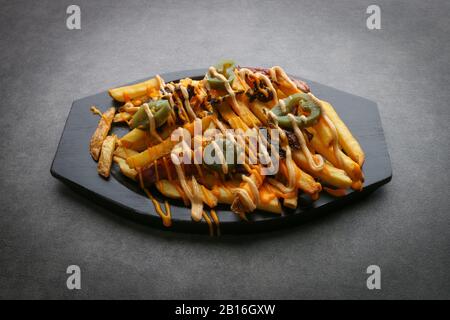 Cheesy fries - French fries with american cheese and cheddar cheese,  close-up on a plate. horizontal view from above Stock Photo