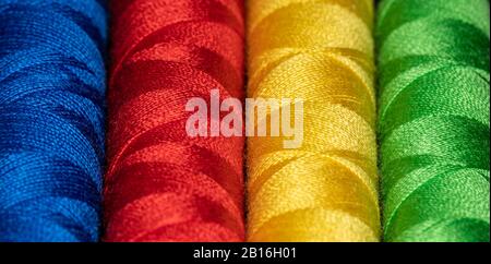 Horizontal cones of bright colored sewing thread in Blue red yellow and green representing Jung personality types Stock Photo