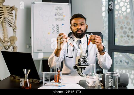 African-american man scientist doctor working in lab making medical research, using laboratory tools, microscope, test tubes, equipment. Biotechnology Stock Photo