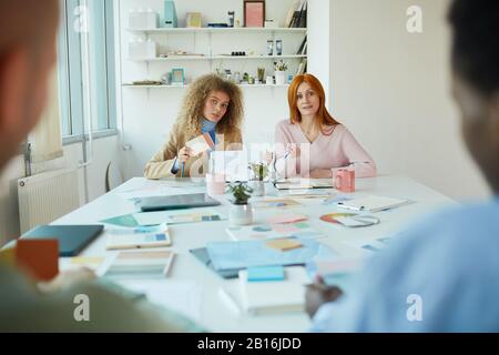 Portrait of two female designers sitting opposite two men while discussing creative project, copy space Stock Photo