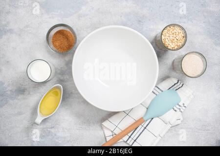Empty bowl and ingredients for baking healthy oat cookies, muffins or cake. Top view flat lay. Kitchen utensils and cooking ingredients on concrete ba Stock Photo