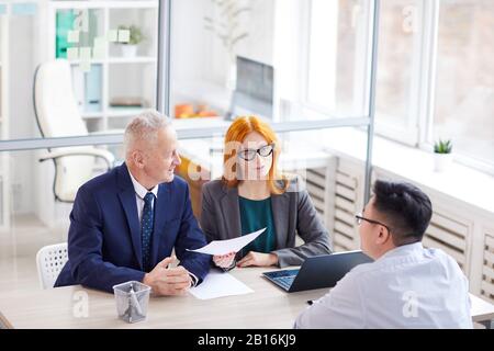 High angle view at two managers interviewing young man for job position in office, copy space Stock Photo