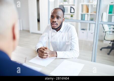 Portrait of contemporary African-American man answering questions to HR manager during job interview in office, copy space Stock Photo