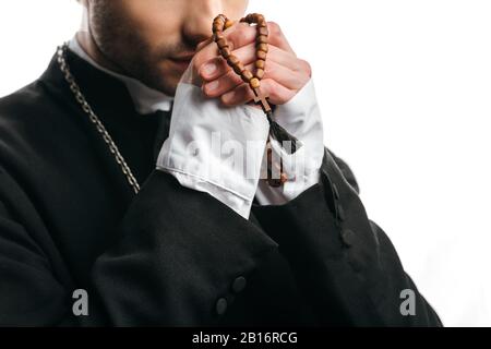 partial view of catholic priest praying while holding wooden rosary beads near face isolated on white Stock Photo