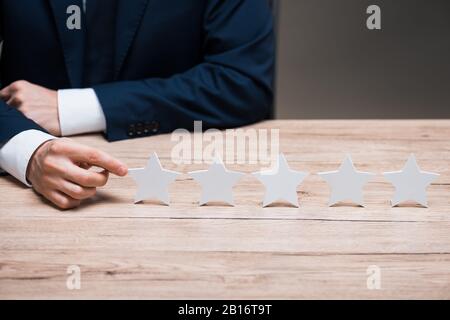 cropped view of man in formal wear pointing with finger at star isolated on grey, quality concept Stock Photo
