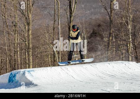 Snowboarder having fun jumping at ski resort in the air from the back Stock Photo