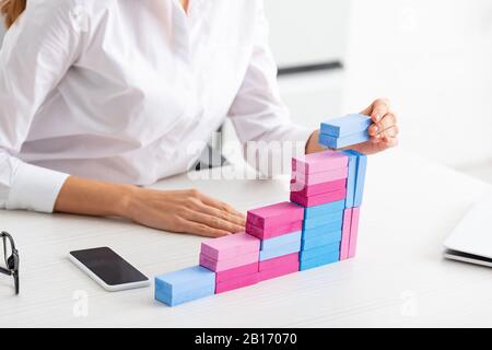 Cropped view of businesswoman stacking marketing pyramid from building blocks on table Stock Photo