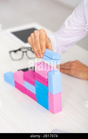 Cropped view of businesswoman making marketing pyramid from colorful building blocks on table Stock Photo