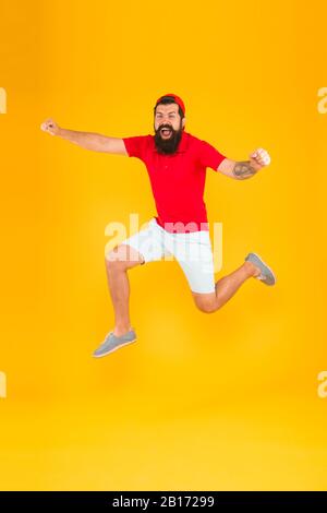 Towards fun. Enjoying active lifestyle. Happy guy jumping. Active bearded man in motion yellow background. Active and energetic hipster. Energy charge. Healthy guy feeling good. Inspired concept. Stock Photo