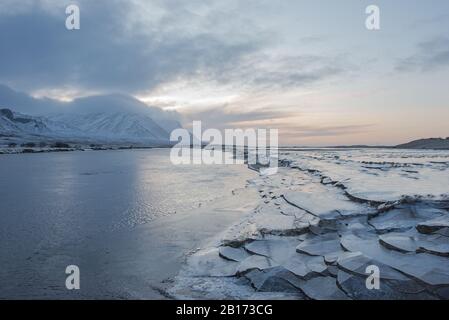 Icy river bank and snow covered mountains in Iceland Stock Photo