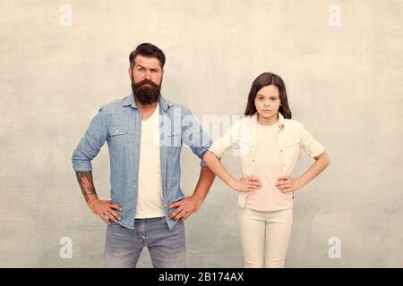 Want to be like my father. Being hero for daughter. Strong temper and confidence. Little child and hipster father on white background. We are team. Bearded father and small girl stand hands on hips. Stock Photo
