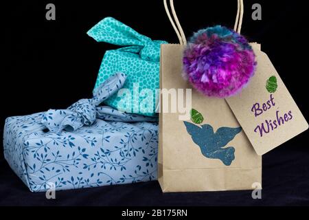 Fabric wrapped gift and homemade pompom on black background. Make, recycle and reuse for sustainable giving for holidays and birthdays, zero waste con Stock Photo