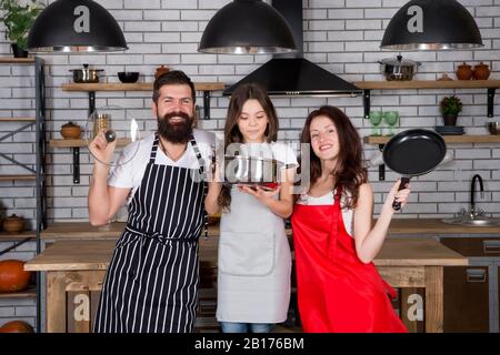 Together is more tasty. Mom dad and daughter aprons in kitchen. Cooking  concept. Prepare delicious breakfast. Lunch time. Family having fun cooking  together. Teach kid cooking food. Cooking together Stock Photo by ©