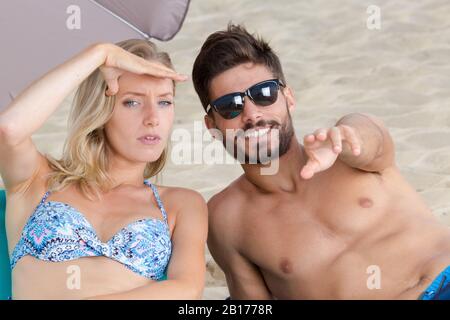 cheerful couple pointing at camera on summer beach Stock Photo