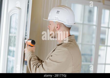 workman using cordless drill on pvc door Stock Photo