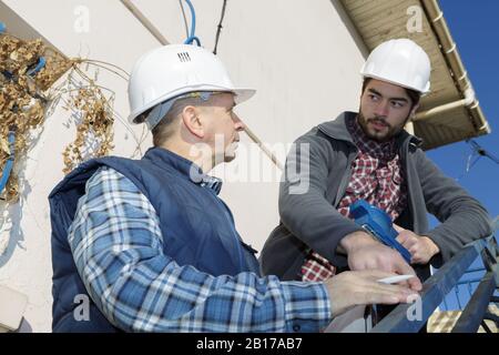 builders in hardhats talking outdoors Stock Photo