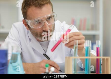 chemist man uses micro pipette to transfer liquid into bottle Stock Photo