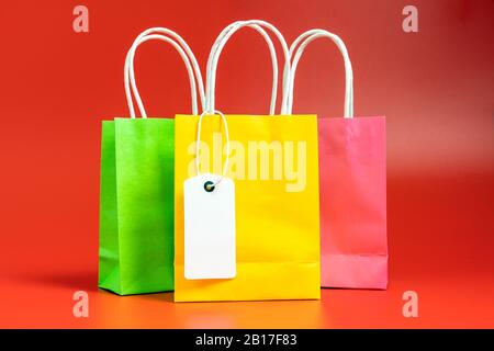 Yellow, green and pink shopping or gift bags isolated on red Stock Photo