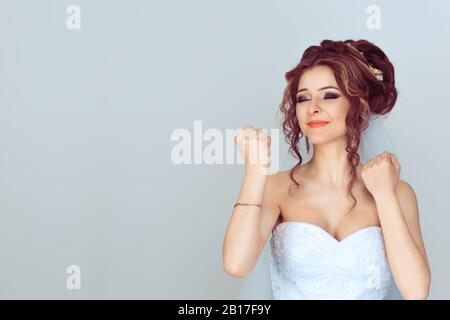 Happy bride woman exults pumping fists ecstatic celebrates success happy of getting married isolated on light blue background Stock Photo