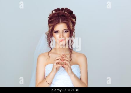 Bride plotting. Closeup portrait sneaky, sly, scheming young woman plotting revenge plan, prankster isolated on light blue wall background. Negative e Stock Photo