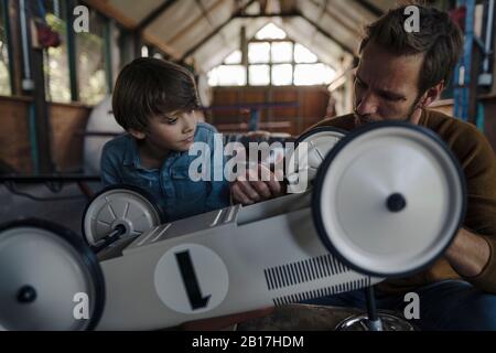 father and son repairing toy car in the barn Stock Photo