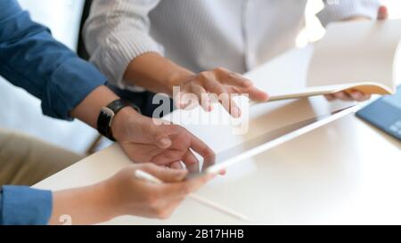 Close up view of two businesspeople consulting on their work with mock up tablet and notebook on white desk Stock Photo