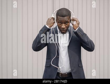 Portrait of young businessman putting on headphones Stock Photo