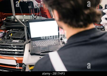Car mechanic in a workshop using laptop Stock Photo