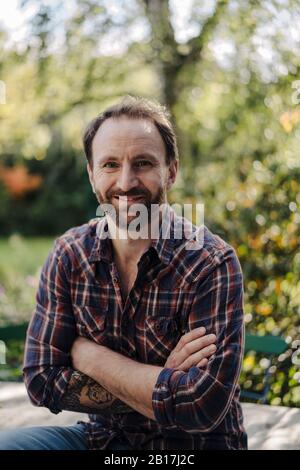 Portrait of mature man in garden, with arms crossed Stock Photo