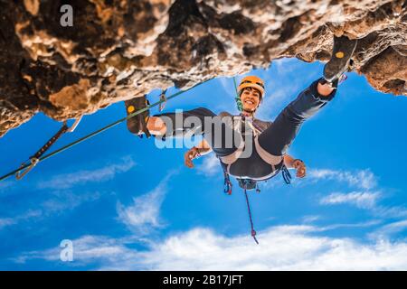Portrait of smiling female climber abseiling from rock face Stock Photo