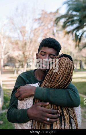 Tenage son hugging mother outdoors Stock Photo