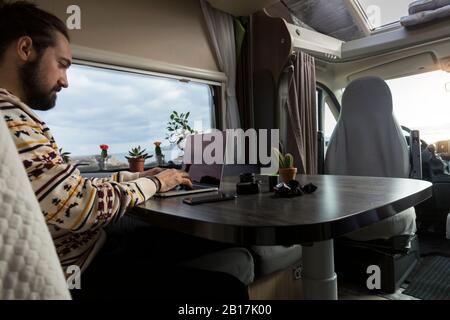 Man working on laptop in his camper, Es Mercadal, Menorca, Spain Stock Photo