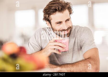 Young man smiling and drinking a fruit smoothie Stock Photo