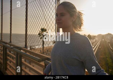 Sporty young woman standing on a bridge in sunshine Stock Photo