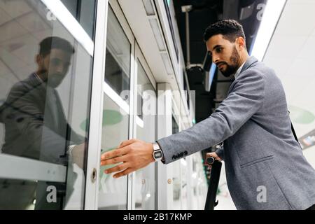 Young businessman pressing the opening button to get on an automatic subway train Stock Photo