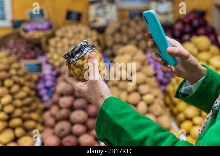 Woman using smartphone app to check a preserving jar Stock Photo